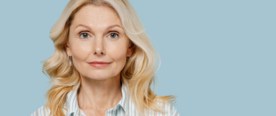 Woman with blonde hair wearing a striped shirt on a blue background.