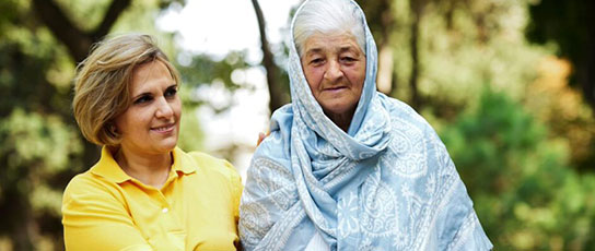Narrow-Block-2 Two people sitting together outdoors, one wearing a yellow shirt and the other draped in a blue patterned shawl.
