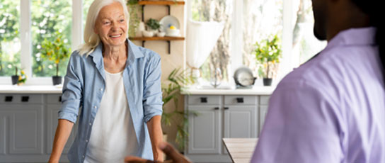 Narrow-Block-michael Two people in conversation in a bright kitchen, focus on the person in the foreground.